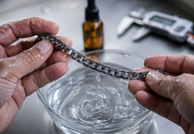 Cliente revisando cadenas de acero quirúrgico en mostrador mayorista